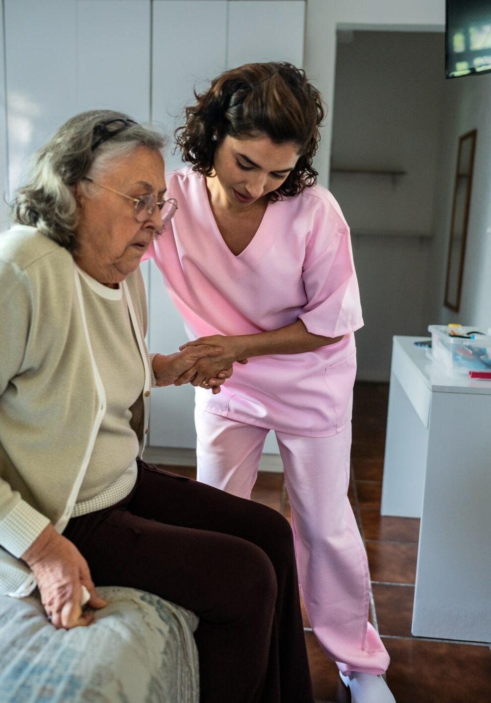 Nurse helping a senior woman sitting in bed at home
